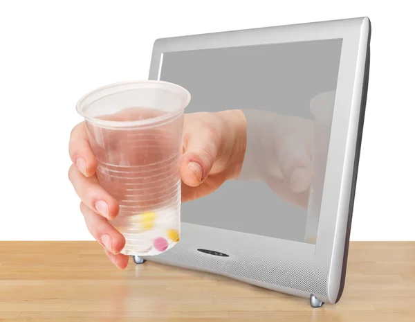 Arm with glass with pills leans out TV screen — Stock Photo, Image