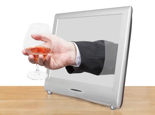 Brandy glass in male hand leans out TV screen — Stock Photo, Image