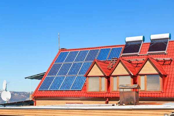 Solar Batteries and heaters on house roof — Stock Photo, Image