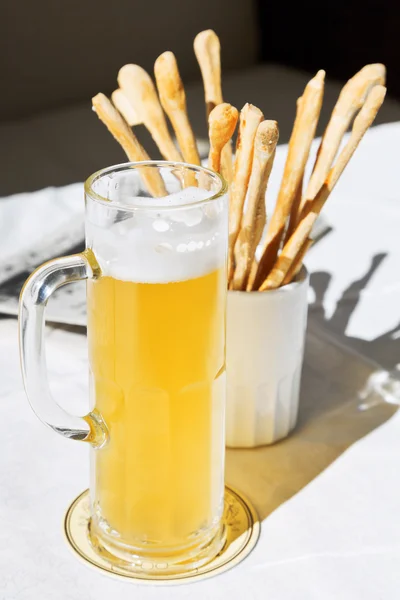 Кружка пива и хлебных палочек на столе — стоковое фото