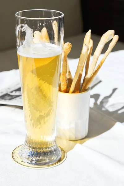 Bicchiere di birra e bastoncini di pane sul tavolo — Foto Stock