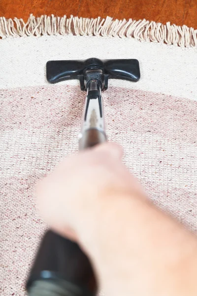 Man cleans carpet with vacuum cleaner — Stock Photo, Image