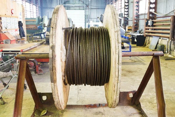 Промышленная деревянная катушка со стальной веревкой в цехе — стоковое фото