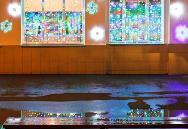 Christmas illumination, wet bench and rain puddle — Stock Photo, Image