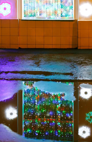 Xmas illumination reflected in melting snow puddle — Stock Photo, Image
