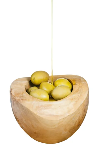Olive oil trickles on green olives in wooden bowl — Stock Photo, Image