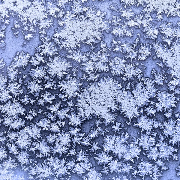 Snowflakes and frost on frozen window in winter — Stock Photo, Image