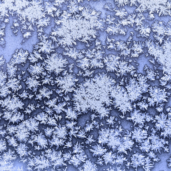 snowflakes and frost on frozen window in winter