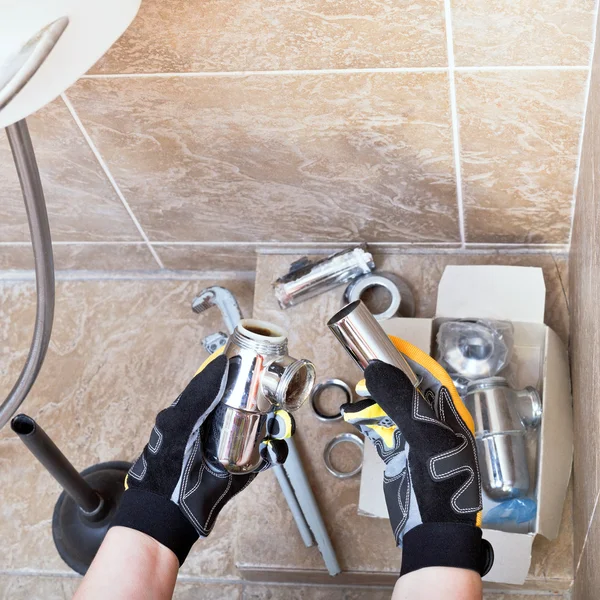 Sanitary technician repairs plumbing trap — Stock Photo, Image