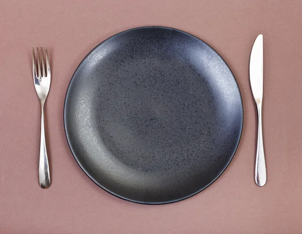 Ovansida av svart plåt, gaffel, kniv på brown — Stockfoto