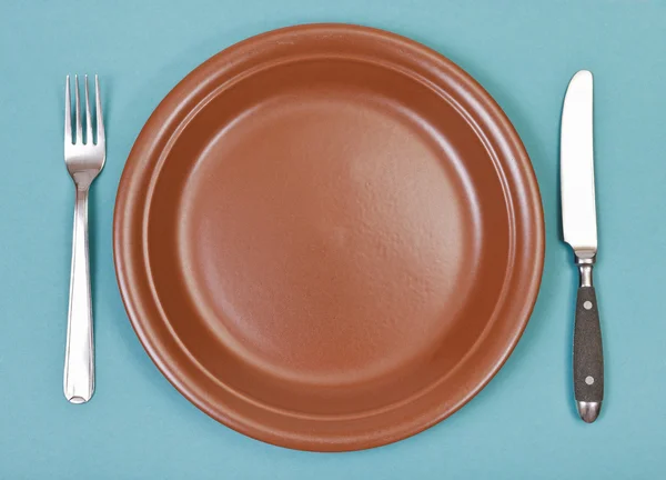Ovansida av keramiska plattan, gaffel, kniv på gröna — Stockfoto