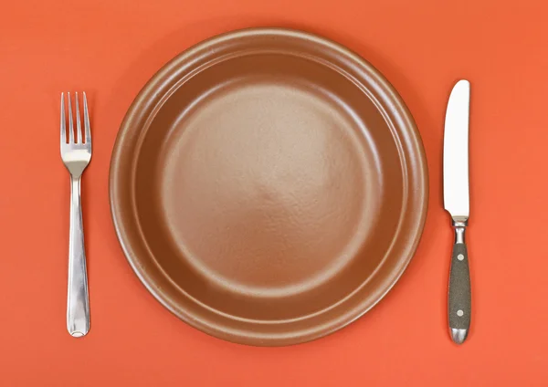 Ovansida av keramiska plattan, gaffel, kniv på rött — Stockfoto