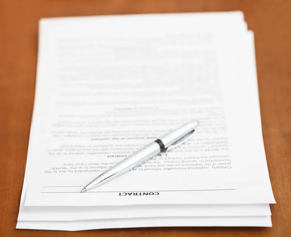 Sales contract and silver pen on wooden table — Stock Photo, Image