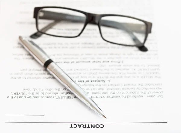 Серебряная ручка и очки по договору продажи — стоковое фото