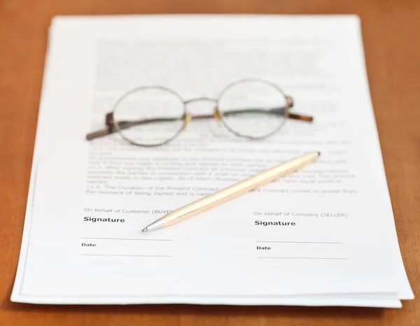 Contrato, pluma de oro y anteojos en la mesa — Foto de Stock