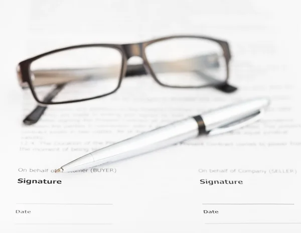 Silver pen and eyeglasses on signature page — Stock Photo, Image
