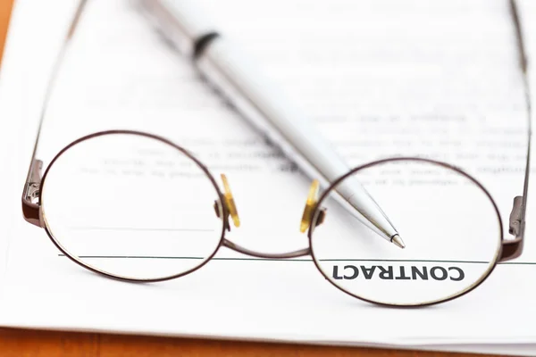 Kontrakt och silver penna genom glasögon — Stockfoto