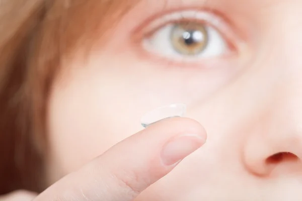 Finger with corrective lens in front of face — Stock Photo, Image