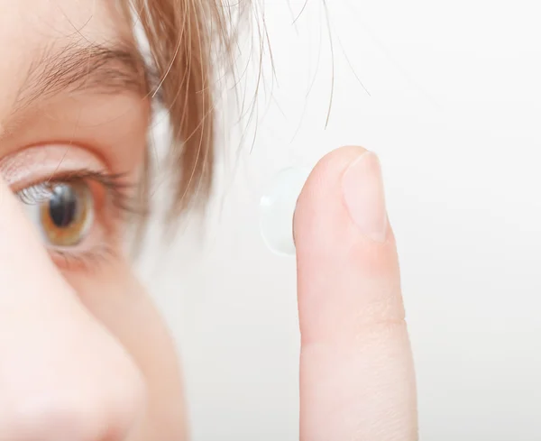 Woman inserts contact lens in eye — Stock Photo, Image