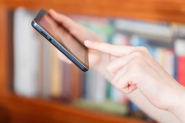 Dedo tocando tablet pc na biblioteca — Fotografia de Stock