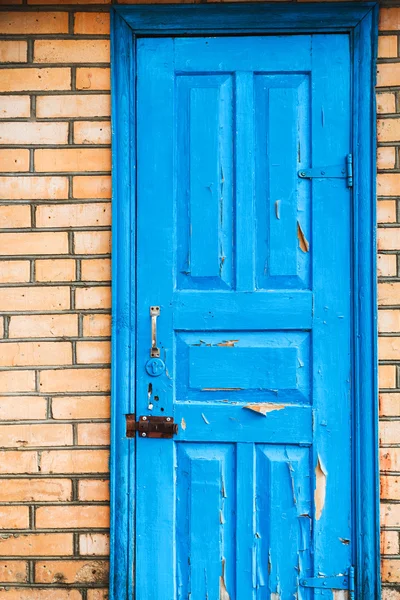 Closed shabby blue door in brick wall — Stock Photo, Image