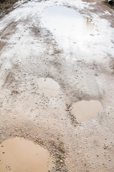 Grond weg met regenachtige plassen in het voorjaar van — Stockfoto