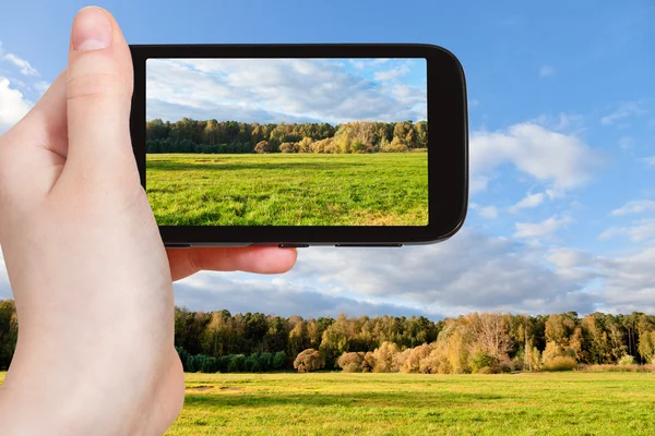 Toeristische nemen foto van groene weide in de herfst — Stockfoto