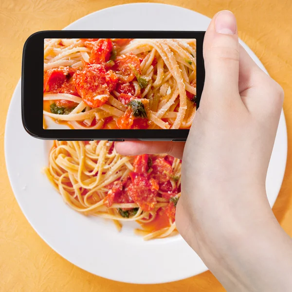 Toeristische nemen foto spaghetti met tomatensaus — Stockfoto