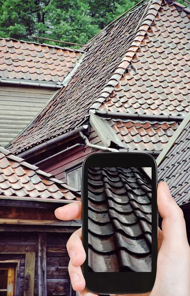 Turista scattare foto tetto di case in legno sotto la pioggia — Foto Stock