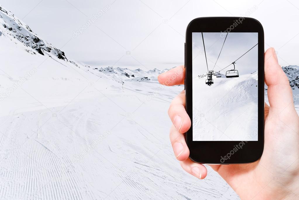 tourist taking photo of skiing tracks and ski lift