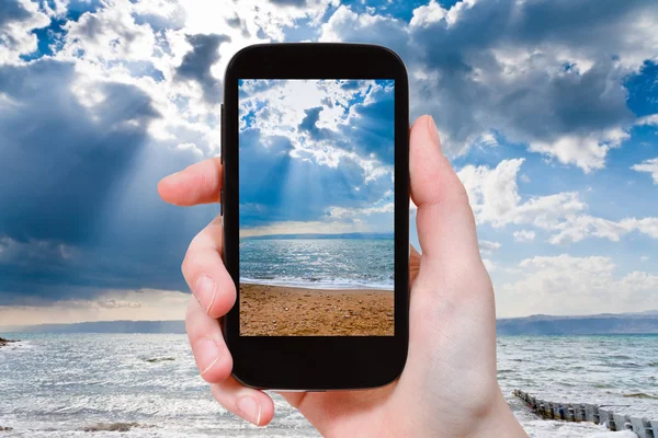 Tourist taking photo of sunbeams over Dead Sea — Stock Photo, Image