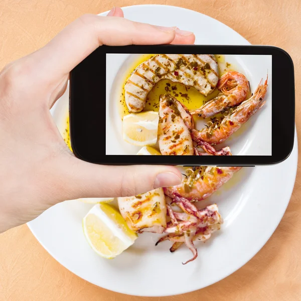 Tourist taking photo of sicilian grilled fish mix — Stock Photo, Image