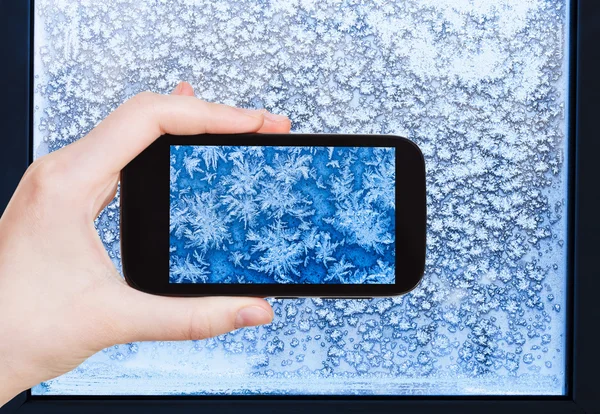 Turist fotograferar snöflingor och frost på fönstret — Stockfoto