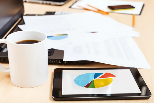 Mug of coffee and tablet pc with chart on desk — Stock Photo, Image