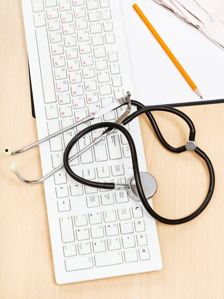 Phonendoscope on white keyboard and clipboard — Stock Photo, Image