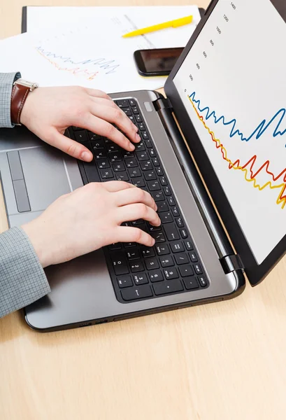 Working with laptop and graph on screen at desk — Stock Photo, Image