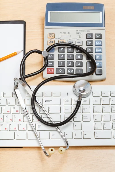 Fonendoscopio en teclado, calculadora, portapapeles —  Fotos de Stock