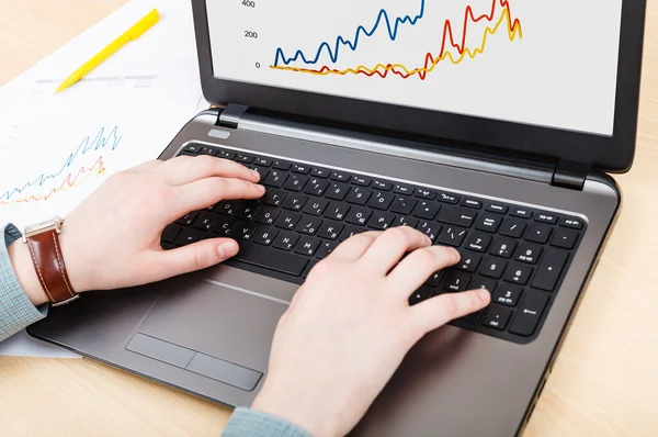Working with laptop and graph on screen at table — Stock Photo, Image