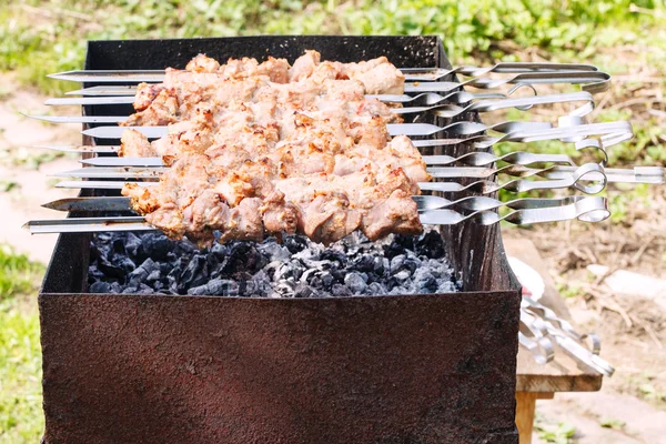 Skewers with shish kebabs on brazier on backyard — Stock Photo, Image