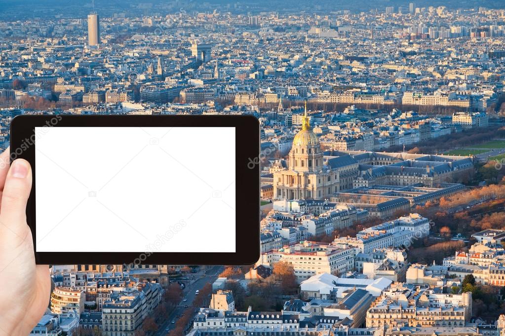 Travel concept - tourist photographs Les Invalides building and panorama of Paris, France in winter afternoon on tablet pc with cut out screen with blank place for advertising logo