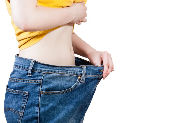 Slim girl trying on large size old jeans isolated — Stock Photo, Image