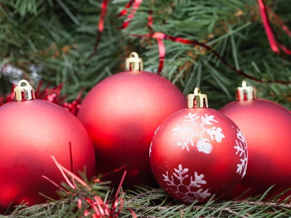 Four red Christmas baubles on Xmas tree background — Stock Photo, Image