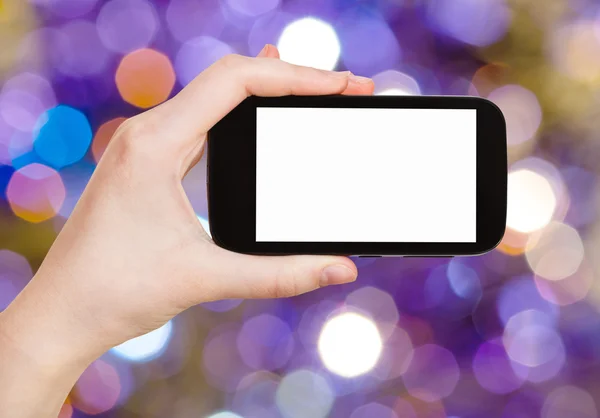 Hand with smartphone on blurred violet background — Stok fotoğraf