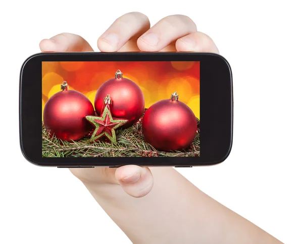 Hand holds handphone with Xmas decorations — Stock fotografie