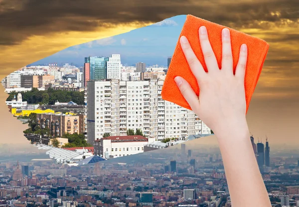 Hand deletes smog in city by orange cloth — Stock Photo, Image