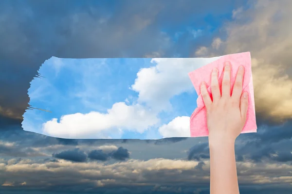 Hand deletes dark cloudscape by pink cloth — Stock Photo, Image