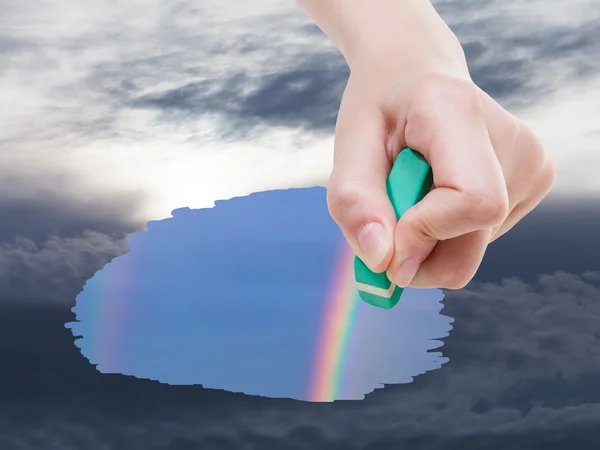 Hand deletes storm clouds on sky by rubber eraser — Stock Photo, Image