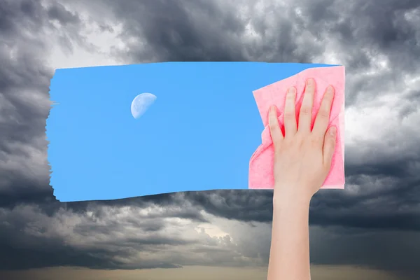 Hand löscht Gewitterwolken mit rosa Tuch — Stockfoto