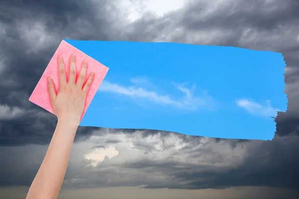 Hand deletes storm clouds by pink cloth — Stock Photo, Image