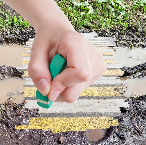 Hand deletes wet road from image by rubber eraser — Stok fotoğraf